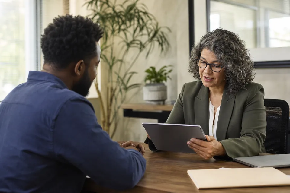 Loan officer reviewing an application on a tablet with a small business owner at a desk
